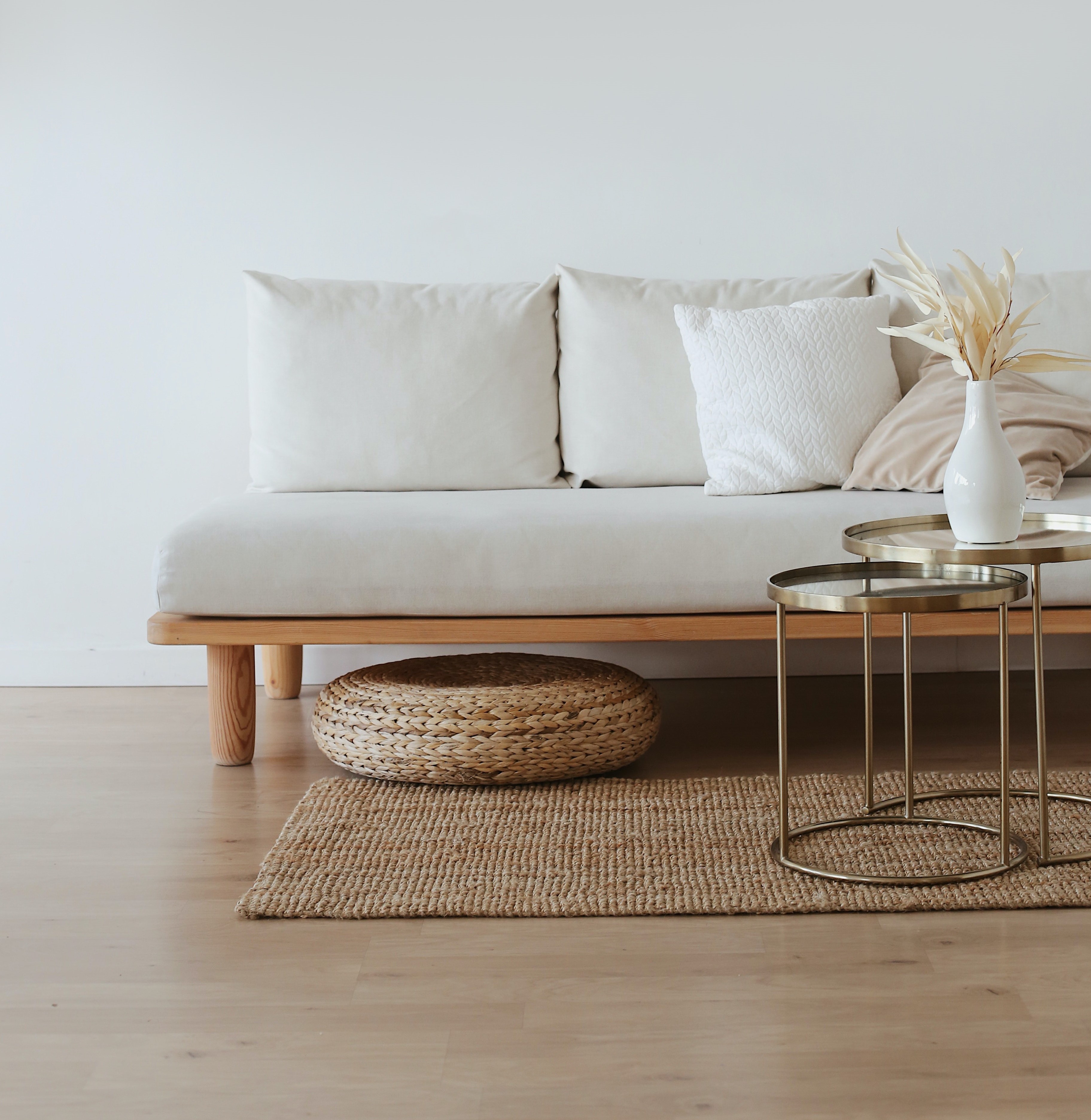 Stock photo featuring white couch, simple wood floor and woven area rug, small coffee table.